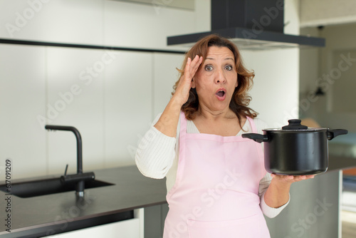 middle age pretty woman looking happy, astonished and surprised. cooking at home concept