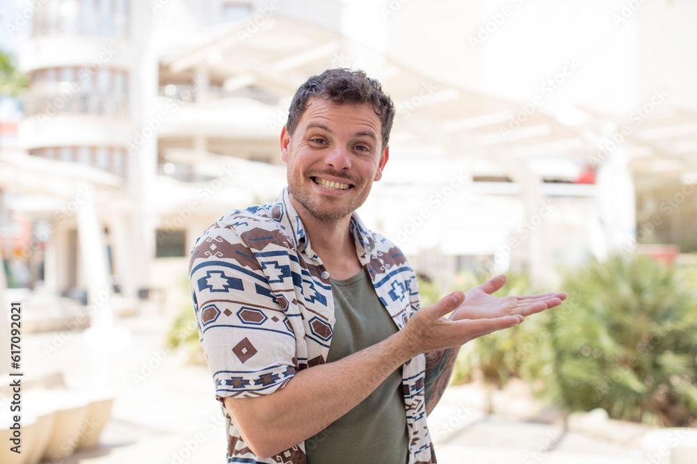 Obraz premium handsome man smiling, feeling confident, successful and happy, showing concept or idea on copy space on the side
