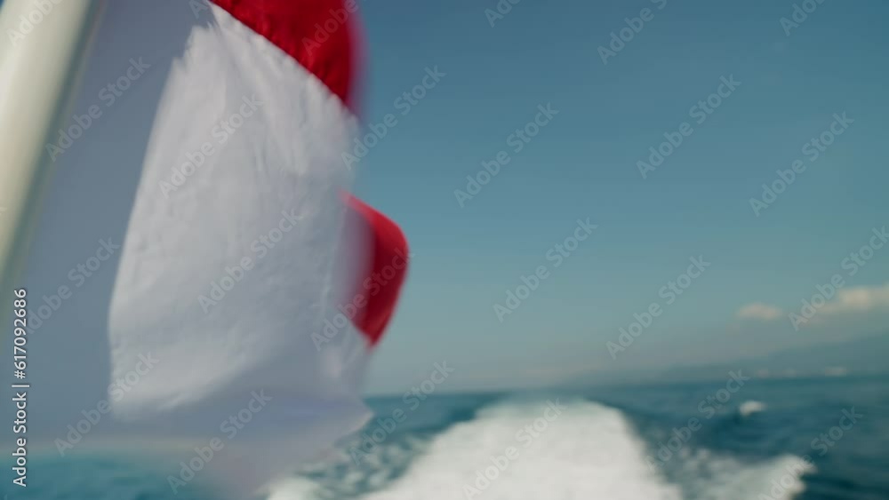 Close-up view of winding Indonesian national symbol. Flag of Indonesia waving in the wind on sea cruise in summer. Slow motion footage of Indonesian flag on sunny day during voyage in open ocean. Close-up view of winding Indonesian national symbol. Flag of Indonesia waving in the wind on sea cruise in summer. Slow motion footage of Indonesian flag on sunny day during voyage in open ocean.