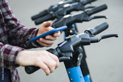 Close up of man hand using mobile app for rental electric scooter.