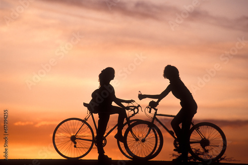 Two teenage girls on bicycles at sunset