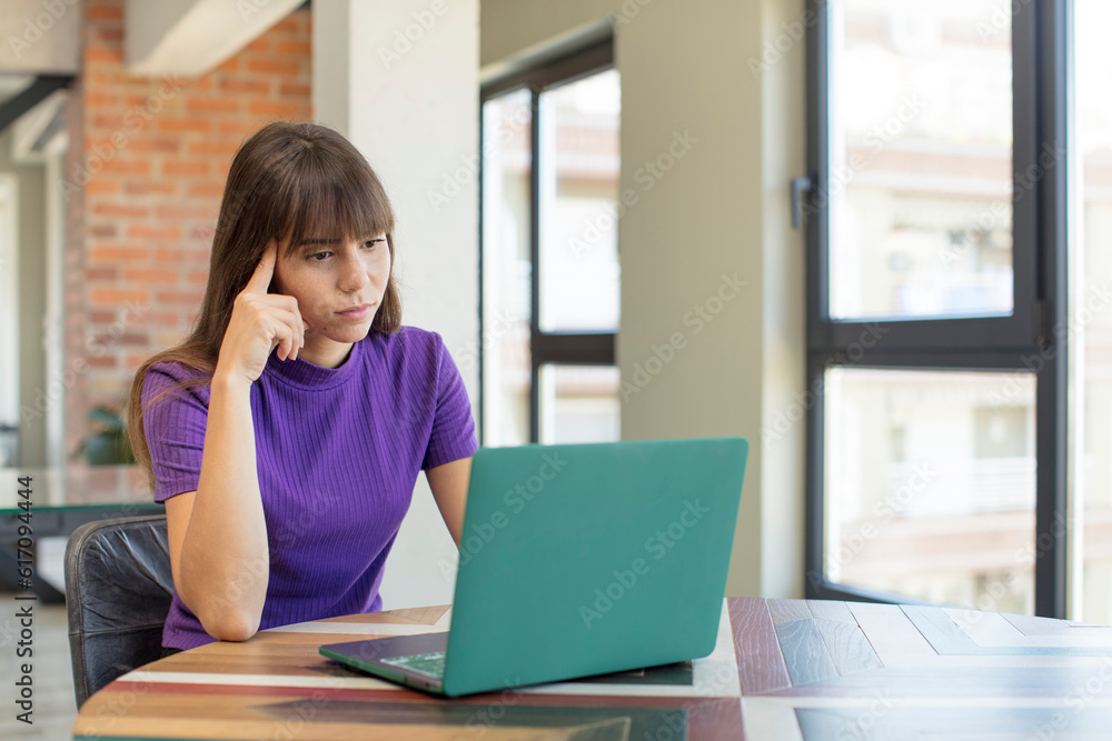 young pretty woman looking surprised, realizing a new thought, idea or concept. desk laptop concept young pretty woman looking surprised, realizing a new thought, idea or concept. desk laptop concept