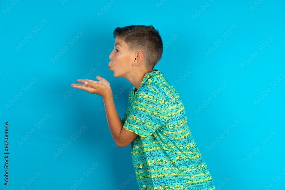 Profile side view, portrait of attractive Little hispanic boy wearing green aztec shirt sending air kiss Profile side view, portrait of attractive Little hispanic boy wearing green aztec shirt sending air kiss