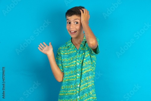 Shocked amazed surprised Little hispanic boy wearing green aztec shirt hold hand offering proposition