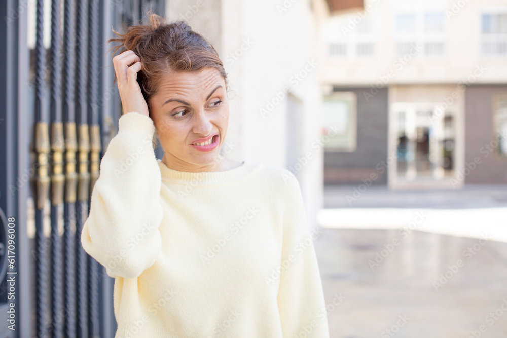 Obraz premium pretty young woman feeling puzzled and confused, scratching head and looking to the side