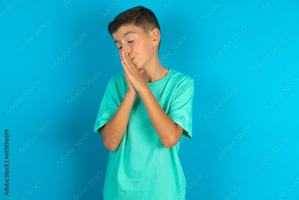 Overjoyed Little hispanic boy wearing green T-shirt laughs joyfully and keeps palms pressed together hears something funny Overjoyed Little hispanic boy wearing green T-shirt laughs joyfully and keeps palms pressed together hears something funny