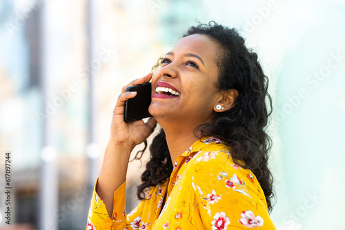 Happy young african american woman talking on cellphone outside