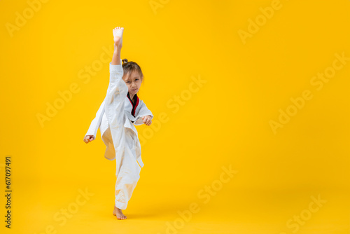 Fotografering Banner: Asian-Australian girl poses in martial arts Practice taekwondo, karate, judo against a yellow background in the studio