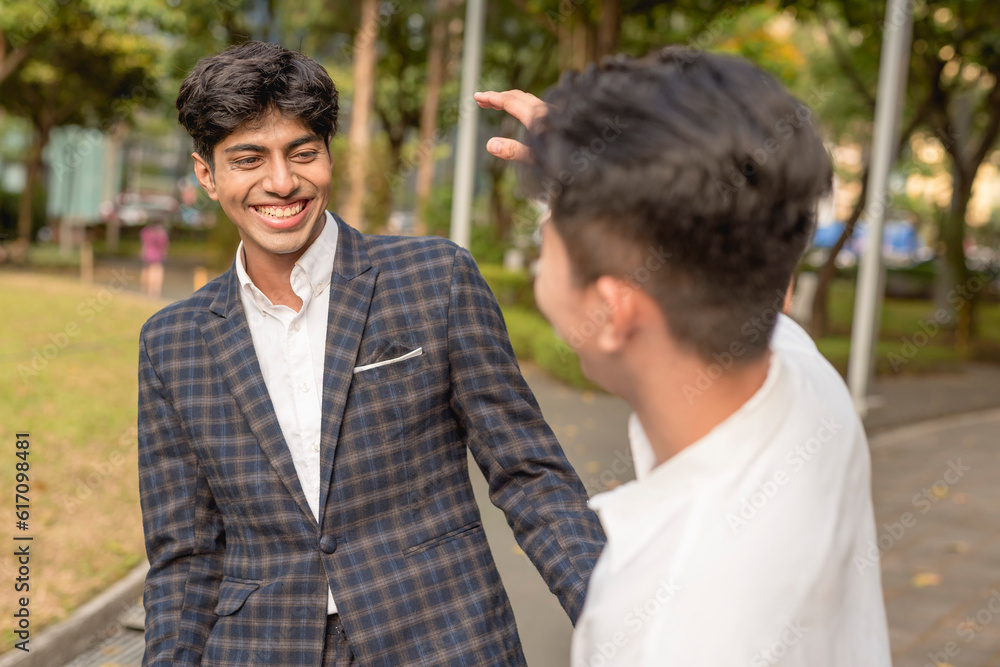 Two young asian men share a lighthearted conversation or shooting the breeze while outside the office.