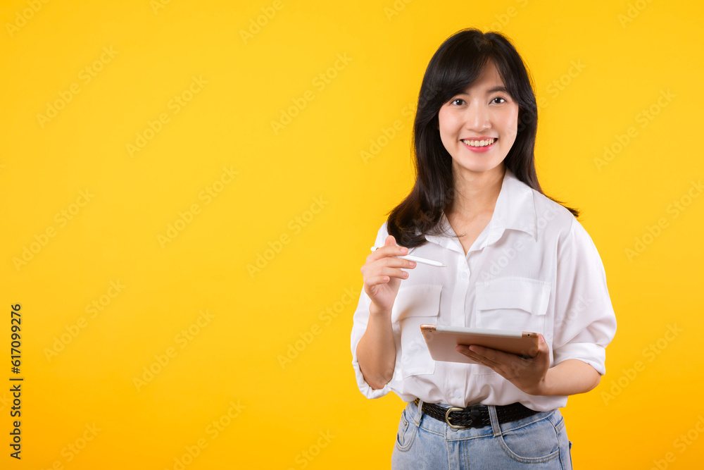asian young businesswoman happy smile woman wearing white shirt and denim jean plants using tablet business management schedule smiling confident cheerful facial expression against yellow background. asian young businesswoman happy smile woman wearing white shirt and denim jean plants using tablet business management schedule smiling confident cheerful facial expression against yellow background.