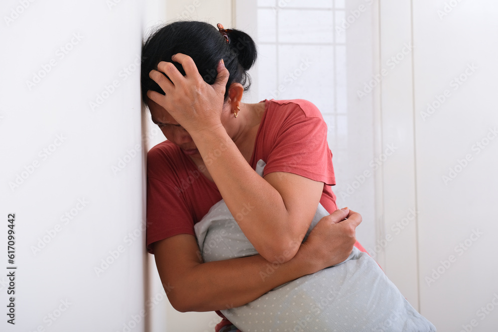 Woman standing, leaning on the wall holding her head under some stress Woman standing, leaning on the wall holding her head under some stress
