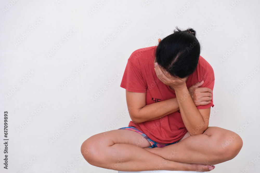 Woman in casual clothes, sitting alone covering her face looking stressful Woman in casual clothes, sitting alone covering her face looking stressful