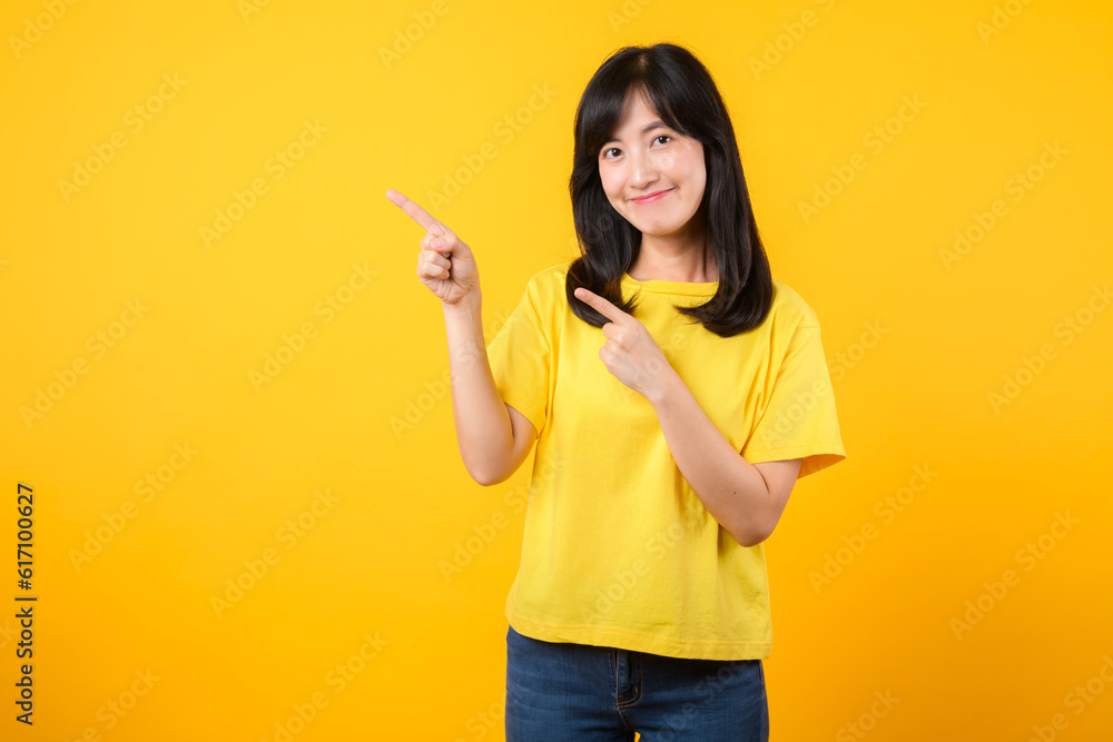 Confident Asian woman pointing to free copy space isolated on yellow studio background Confident Asian woman pointing to free copy space isolated on yellow studio background