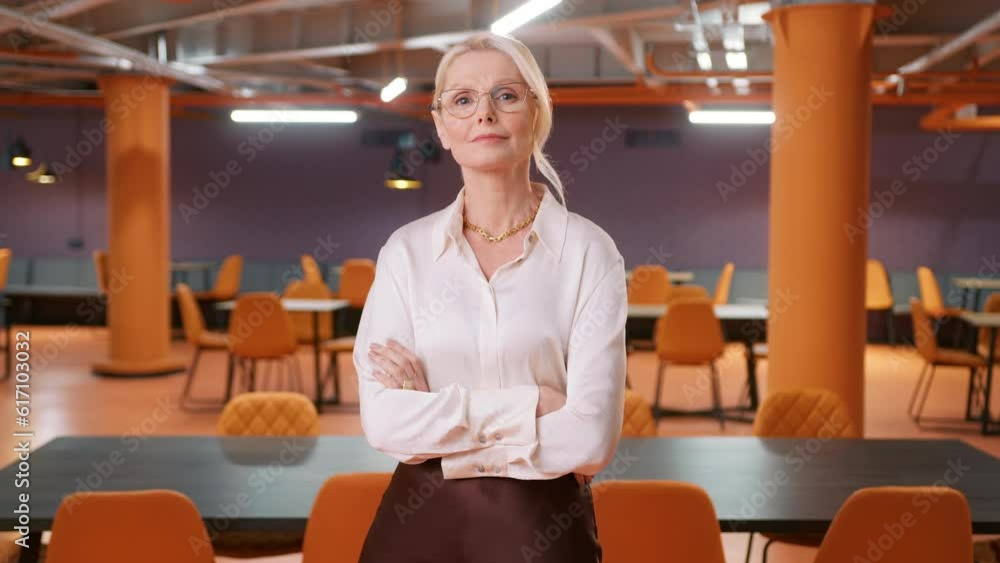 Smart confident mature CEO woman in eyeglasses posing crossing arms at empty business office space background. Caucasian 50s successful confident strong businesswoman corporate manager lady boss 4K Smart confident mature CEO woman in eyeglasses posing crossing arms at empty business office space background. Caucasian 50s successful confident strong businesswoman corporate manager lady boss 4K