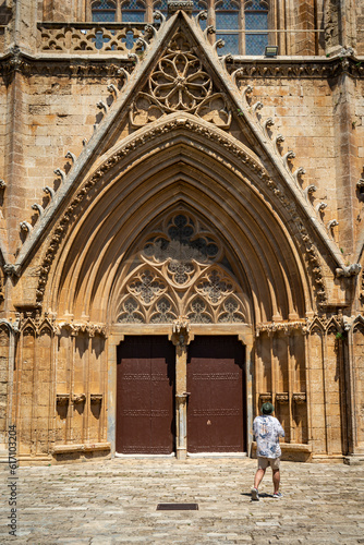 Lala Mustafa Pasha Camii Mosque or old Cathedral of Saint Nicholas in Famagusta or Gazimagusa historical city centre with a tourist in front, Northern Cyprus. Selective focus.