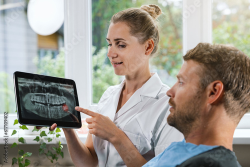 dentist showing and explaining dental x-ray picture with impacted wisdom tooth to his patient