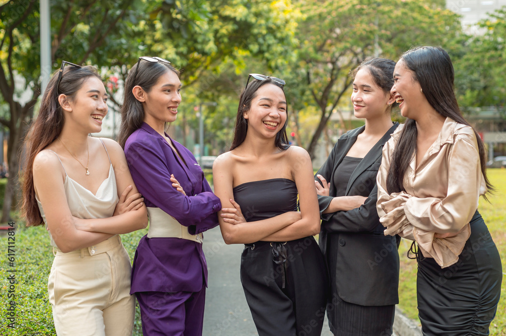 5 asian women, possibly workmates at the office, having a lighthearted discussion while taking a walk at the park.
