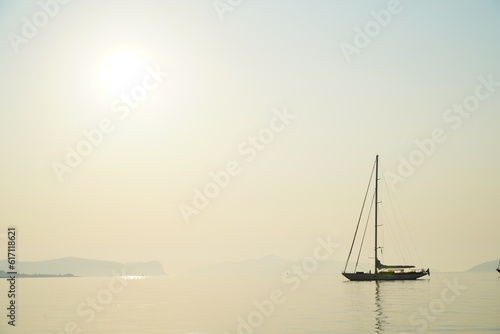 Silhouette of a sailing boat on a calm see against the morning sun, taken from the island of Spetses in the Aegean Sea, Greece