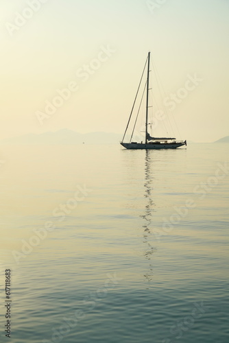 Silhouette of a sailing yacht in early morning sunlight, island of Spetses, Aegean Sea, Greece