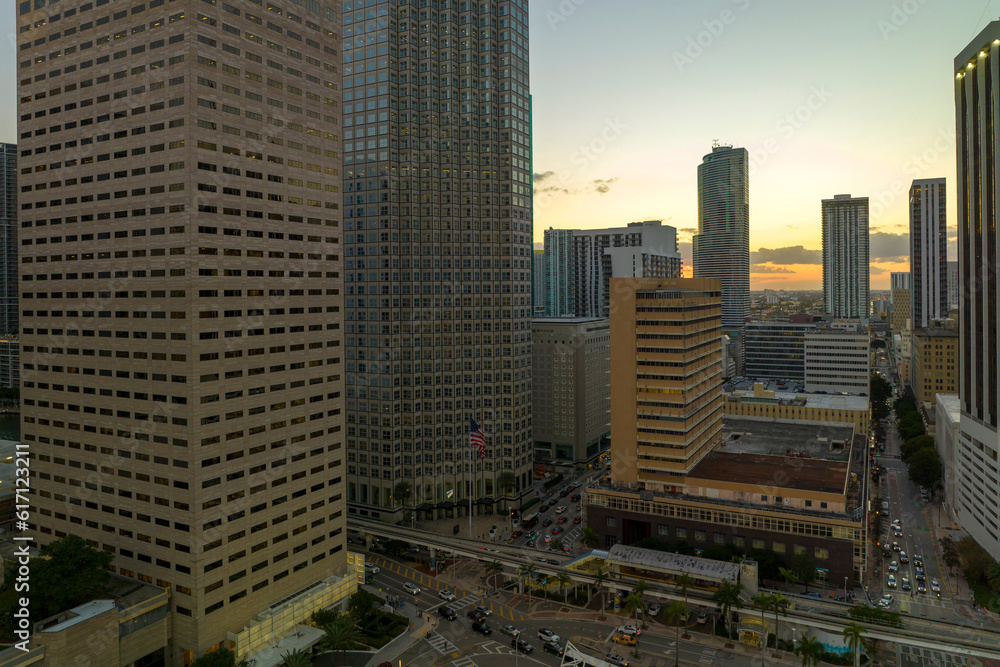 Obraz premium Aerial view of downtown district of of Miami Brickell in Florida, USA at sunset. High skyscraper buildings and street with cars and Metrorail traffic in modern american midtown