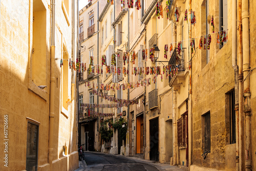 A narrow alley decorated with colorful flags in the downtown of the French city of Montpellier in France
