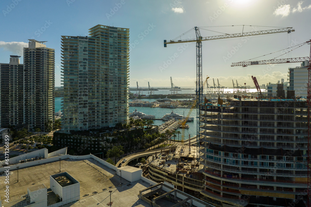 New construction site of developing residense in american urban area. Industrial tower lifting cranes in Miami, Florida. Concept of housing growth in the USA