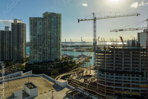 New construction site of developing residense in american urban area. Industrial tower lifting cranes in Miami, Florida. Concept of housing growth in the USA