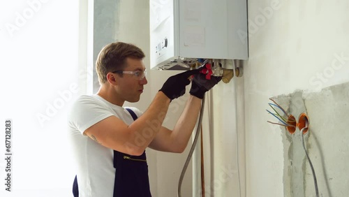 Professional engineer installing a natural gas boiler at home, he is checking the pipes