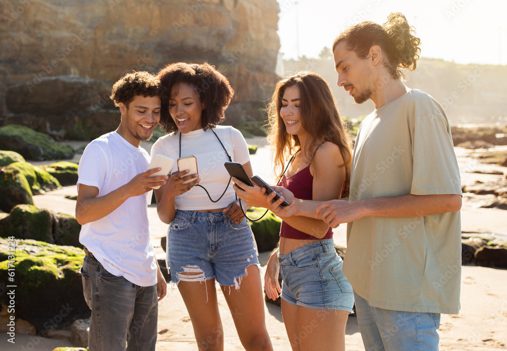 Cheerful millennial international people students enjoy summer holidays, have fun, chatting on smartphones Cheerful millennial international people students enjoy summer holidays, have fun, chatting on smartphones
