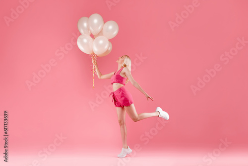 Full length shot of romantic lovely blonde lady holding baloons want to fly up, posing isolated on pink color background