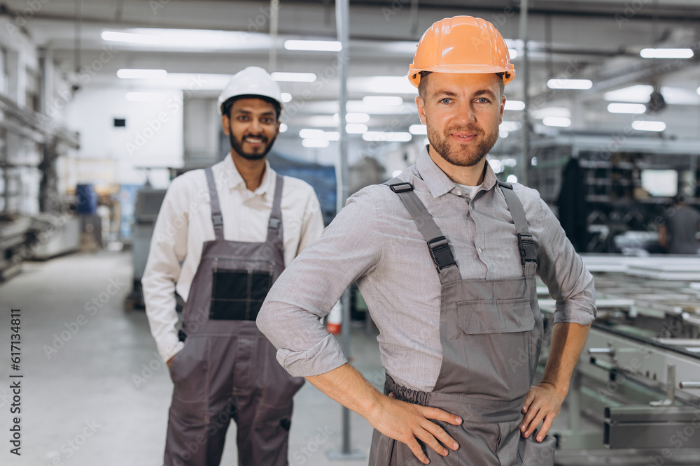 Two international male workers in overalls on the background of the production of PVC windows and doors Two international male workers in overalls on the background of the production of PVC windows and doors