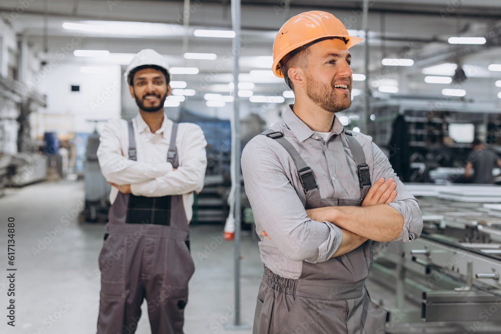 Two international male workers in overalls on the background of the production of PVC windows and doors Two international male workers in overalls on the background of the production of PVC windows and doors