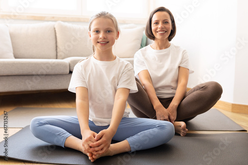 Positive millennial caucasian woman in sportswear and teenage daughter practice yoga, training