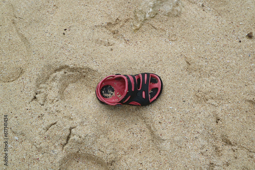 Black and red children shoe lost on the sandy beach