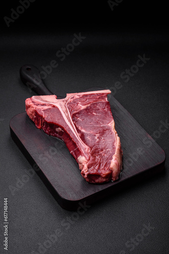 Raw juicy beef t-bone steak with salt, spices and herbs
