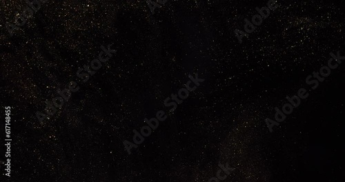 Natural moving black background with gold and silver sequins. The space of flying particles.