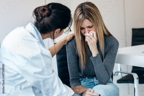 Beautiful worried woman crying while doing therapy with her female psychologist at the medical consultation