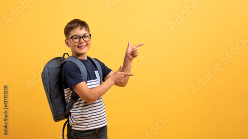 Canvastavla Happy boy schooler pointing at copy space, isolated on yellow