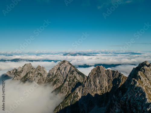 Rocky mountains rising above clouds. Photo taken with a drone. Julian Alps, Slovenia.