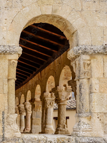 Stone columns with different carvings seen through a window with a semicircular arch