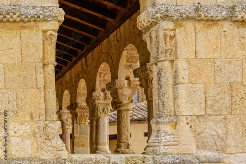 Stone columns with different carvings seen through a window with a semicircular arch