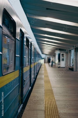 Blue-yellow subway train cars at the elevated station in the evening in the Ukrainian subway. Departures of subway cars from an empty subway station leaving perspective. Open train windows