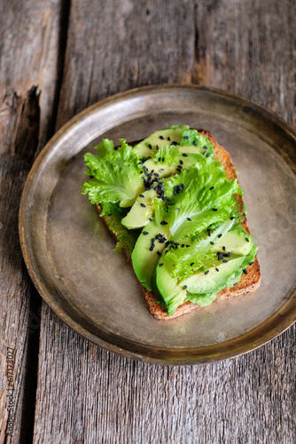 toast with lettuce, avocado, black sesame. homemade bread. Top view. Wooden background.