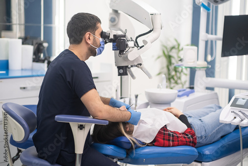 Professional dentist treating teeth of female patient looking in dental microscope woman lying on chair taking dentistry services innovative equipment in modern clinic