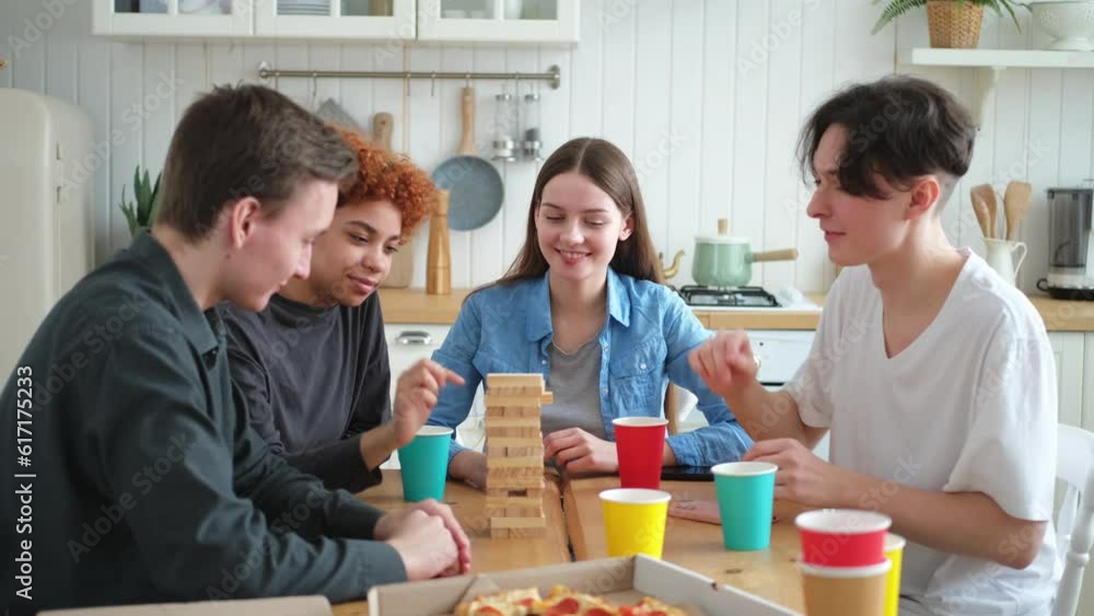 Home party. Friends spending time together playing in board game crash wooden tower at home. Happy diverse group having fun together indoor. Mixed race young buddies best friends enjoying weekend Home party. Friends spending time together playing in board game crash wooden tower at home. Happy diverse group having fun together indoor. Mixed race young buddies best friends enjoying weekend