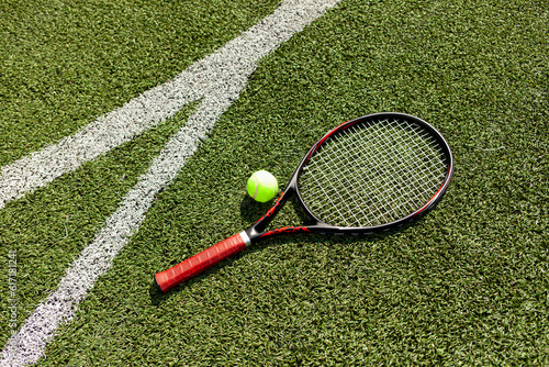 professional tennis racket with ball lies on green court, tennis equipment on the floor