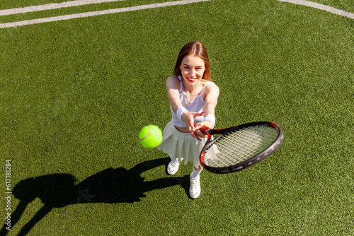 young girl tennis player in white sports uniform plays tennis on green court, woman coach with tennis racket