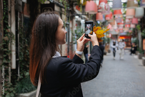 Woman taking photo with phone in the street in China back view