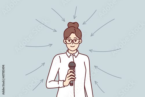 Business woman with microphone stands among arrows for concept of participation in professional seminar or conference. Girl business coach holds mic motivating company team for productive work