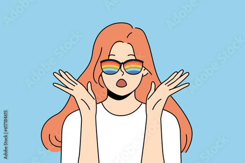 Woman with rainbow glasses exclaims loudly and makes gesture of surprise when sees unusual phenomenon or hears exciting news. Shocked girl in sunglasses with rainbow stripes looks at screen
